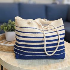 a blue and white striped bag sitting on top of a table next to a potted plant