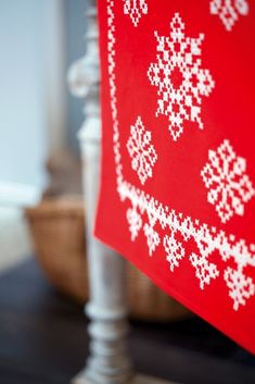 a red flag with white snowflakes hanging from it's side on a table