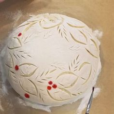 a person is making a cake with white frosting and red decorations on it,