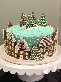 a decorated christmas cake sitting on top of a white platter covered in frosting