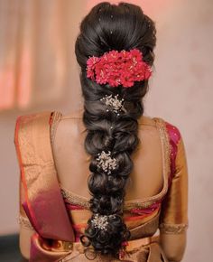 a woman with long black hair wearing a red flower in her hair and an intricate braid