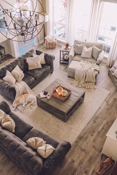 a living room filled with furniture and a chandelier hanging from the ceiling in front of two windows