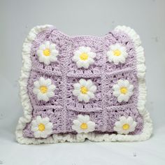 a crocheted pillow with white and yellow flowers