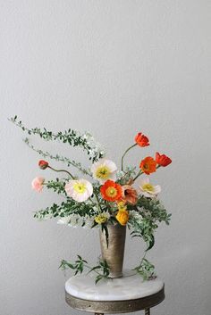 a vase filled with flowers sitting on top of a white table next to a wall