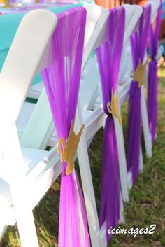 purple and white chairs are lined up on the grass