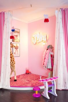 a room with pink walls, curtains and a giraffe in the corner