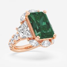 an emerald and diamond ring with three diamonds on each side, set in 18k rose gold