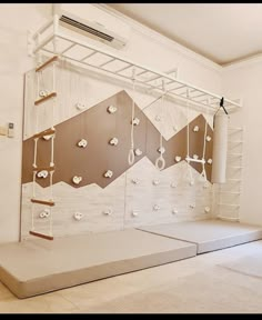 an empty room with white walls and wooden shelves on the wall are suspended by ropes