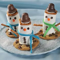 four marshmallow snowmen on top of cookies