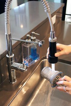 a person is washing their hands under a faucet in a kitchen with stainless steel counter tops