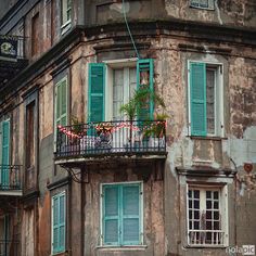 an old building with green shutters and balconies on the second story balcony