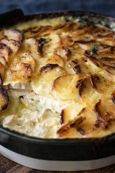 a casserole dish with potatoes and meat in it on a wooden table top