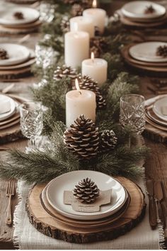 the table is set with pine cones, candles and place settings for an elegant christmas dinner