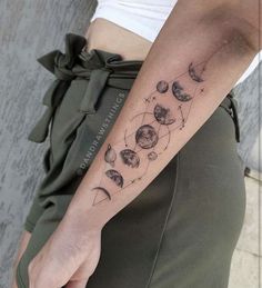 a woman's arm with phases of the moon and stars tattooed on her left arm