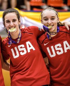 three women in red shirts standing next to each other with gold medals on their mouths