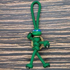 a green rope with a yellow hat on it's head hanging from a hook