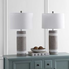 two lamps sitting on top of a table next to a bowl with fruit in it