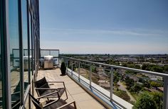 a balcony with chairs and tables overlooking the city