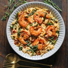 pasta with shrimp and spinach in a white bowl on top of a wooden table