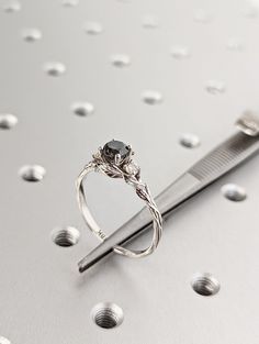 a diamond ring sitting on top of a metal object next to a comb and screwdriver