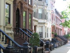 a row of browns and white townhouses with balconies on the front steps