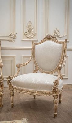 an ornately decorated chair sits in the middle of a room with white walls and wood floors