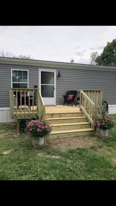 a mobile home with steps leading up to the front door and flowers on the lawn