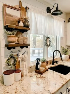 a kitchen with white cabinets and marble counter tops, an open window over the sink