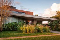 the house is surrounded by lush green grass and tall trees, along with some bushes