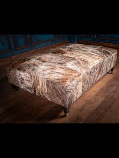 a large footstool sitting on top of a wooden floor next to a blue wall