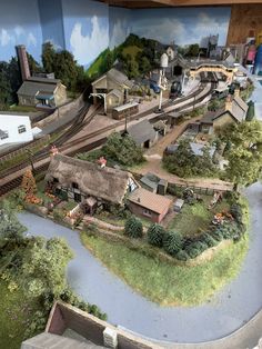 a model train set is shown in front of a wall with an image of a village on it