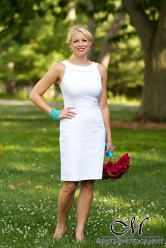 a woman standing in the grass with her hands on her hips wearing a white dress