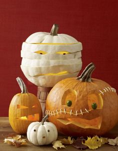 three carved pumpkins sitting on top of a wooden table