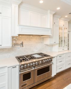 a large kitchen with white cabinets and stainless steel stove top oven in the center of the room