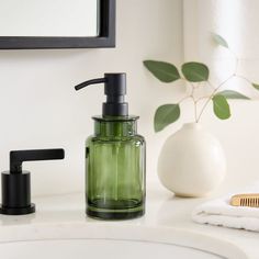 a green soap dispenser sitting on top of a bathroom counter next to a brush