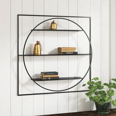 a black metal shelf with books on it next to a potted plant and white wall