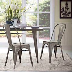 two metal chairs sitting at a table in front of a window