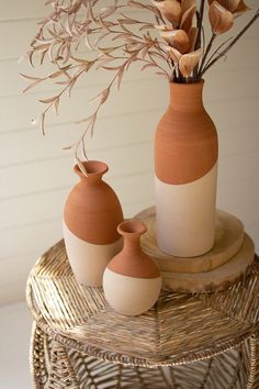 two vases with flowers in them sitting on a wicker table next to each other