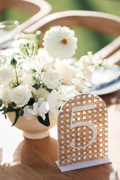 a table with white flowers and a card on it that says 5 in the center