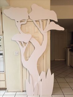 a white door with a tree cut out of it's side in front of a tile floor