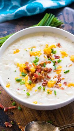 a white bowl filled with soup and topped with bacon, green onions and chives