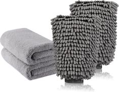 two gray towels stacked on top of each other next to the same folded towel in front of one another