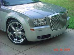 a silver car parked on the side of a road next to a grass covered field