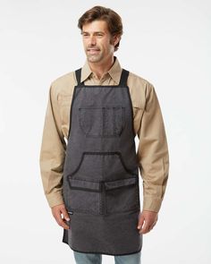 a man wearing an apron and smiling at the camera with his hands in his pockets