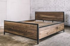 a bed frame made out of wood with metal legs and headboard, against a white brick wall