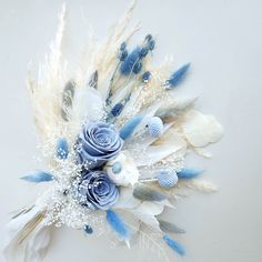 an arrangement of feathers and flowers on a white tablecloth with some blue roses in the center