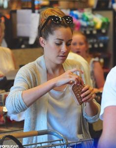 a woman holding a chocolate bar in her hand while standing next to other people at a store