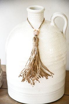 a white vase with a tassel hanging from it