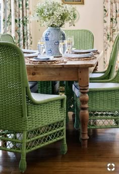 a dining room table with green chairs and a blue vase on top of the table