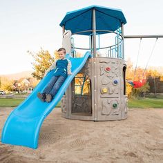 a young boy sliding down a slide at a playground